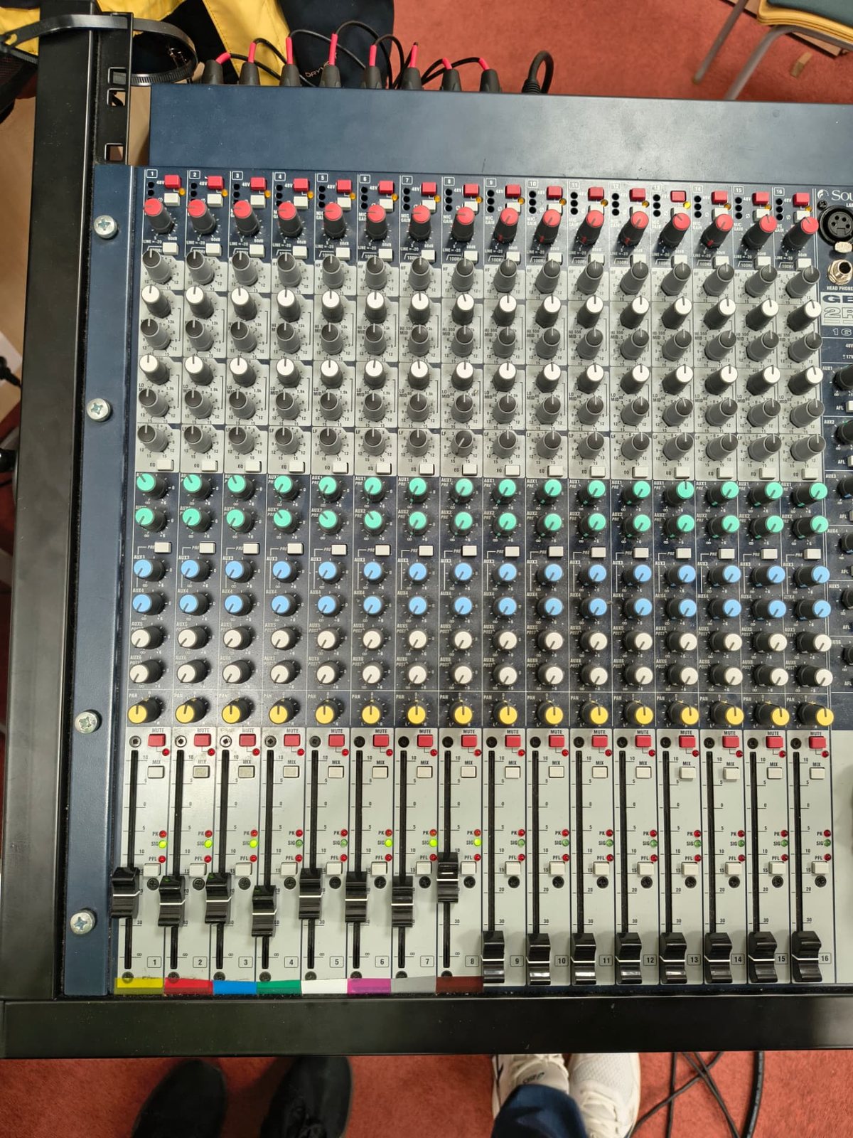 Pohled shora na analogový mixážní pult Soundcraft GB2R 16 s fadery a barevnými potenciometry